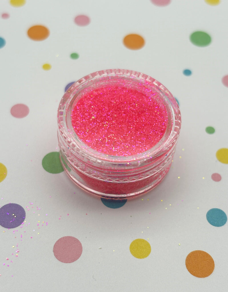 a small jar of pink glitter sitting on top of a table