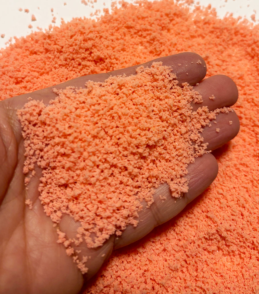 a hand holding a pile of orange powder