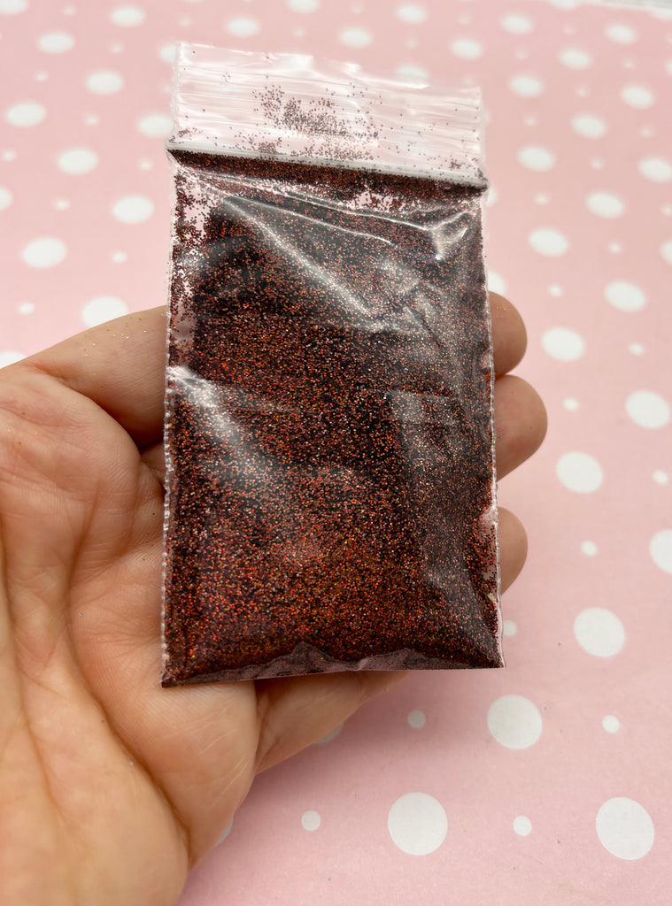 a hand holding a bag of brown glitter