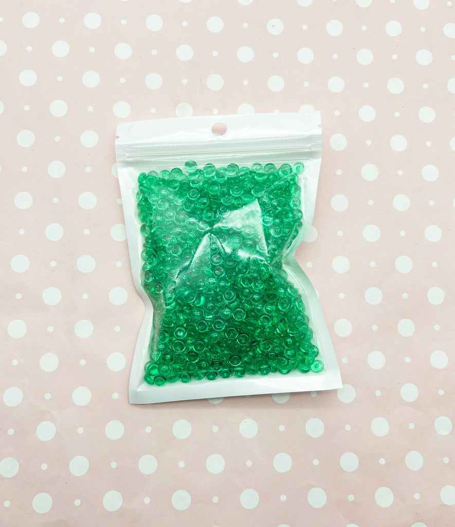 a bag of green beads sitting on top of a table