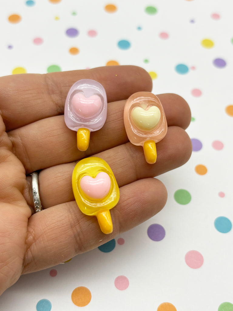 a person is holding three lollipops in their hand