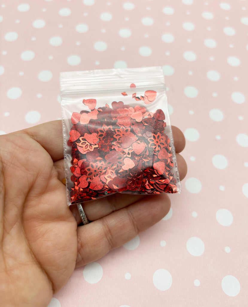 a hand holding a bag of red confetti