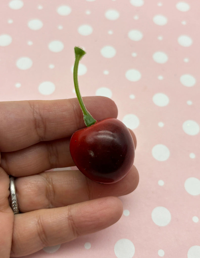 a tiny cherry being held in a persons hand