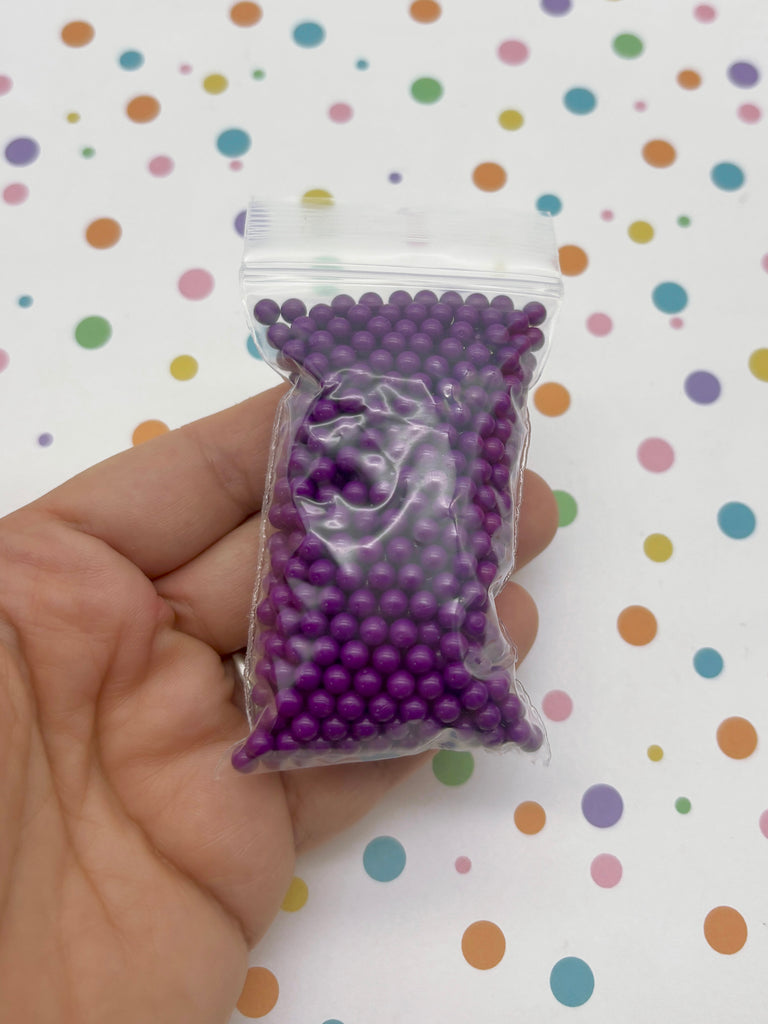 a hand holding a bag of purple beads