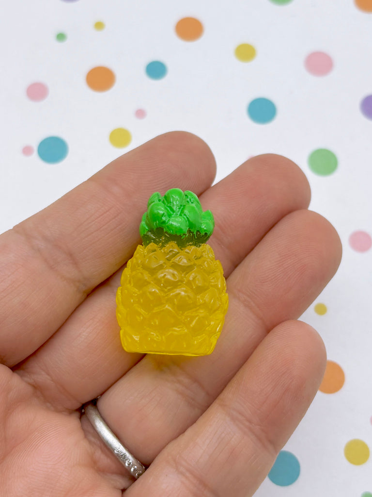 A hand holding a small, yellow and green pineapple-shaped object against a background with colorful polka dots.