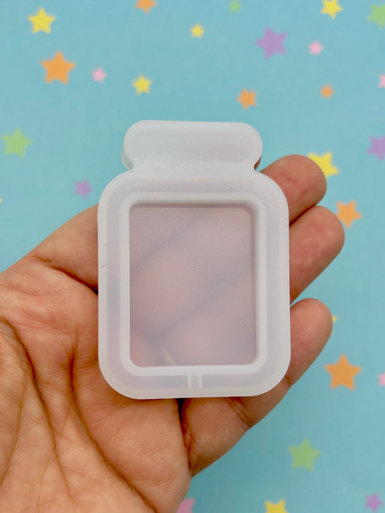 a hand holding a plastic container with a small window