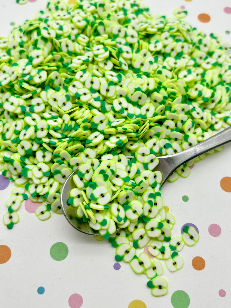 a spoon full of green sprinkles sitting on top of a table
