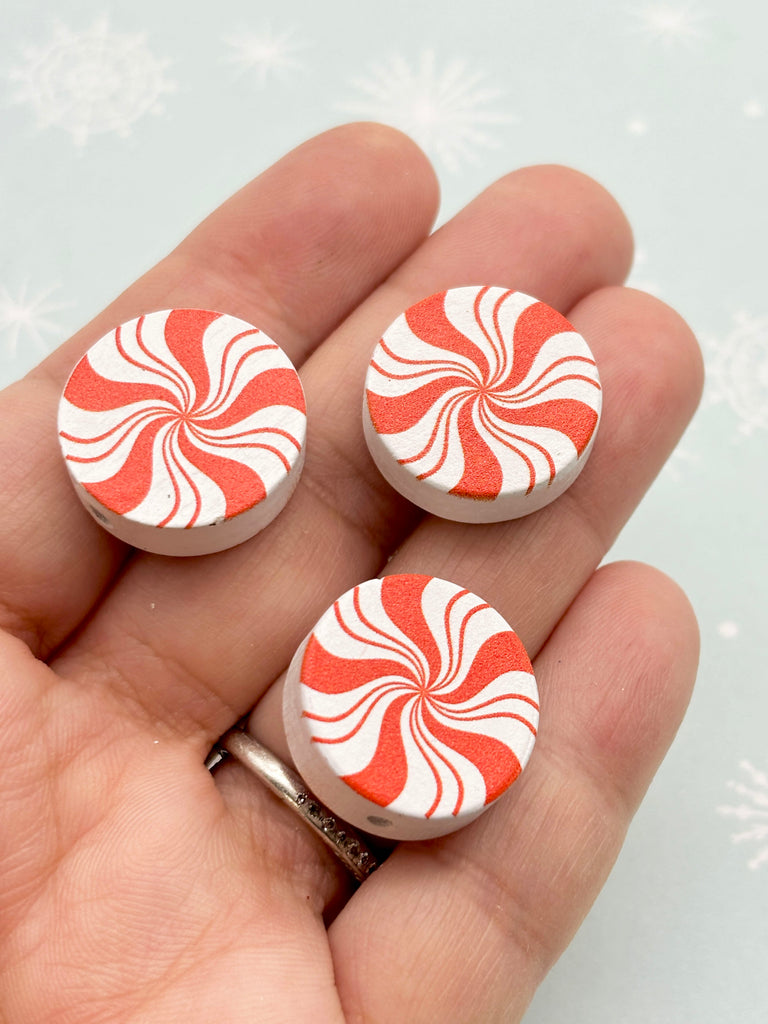 a person holding a pair of red and white candy cane buttons
