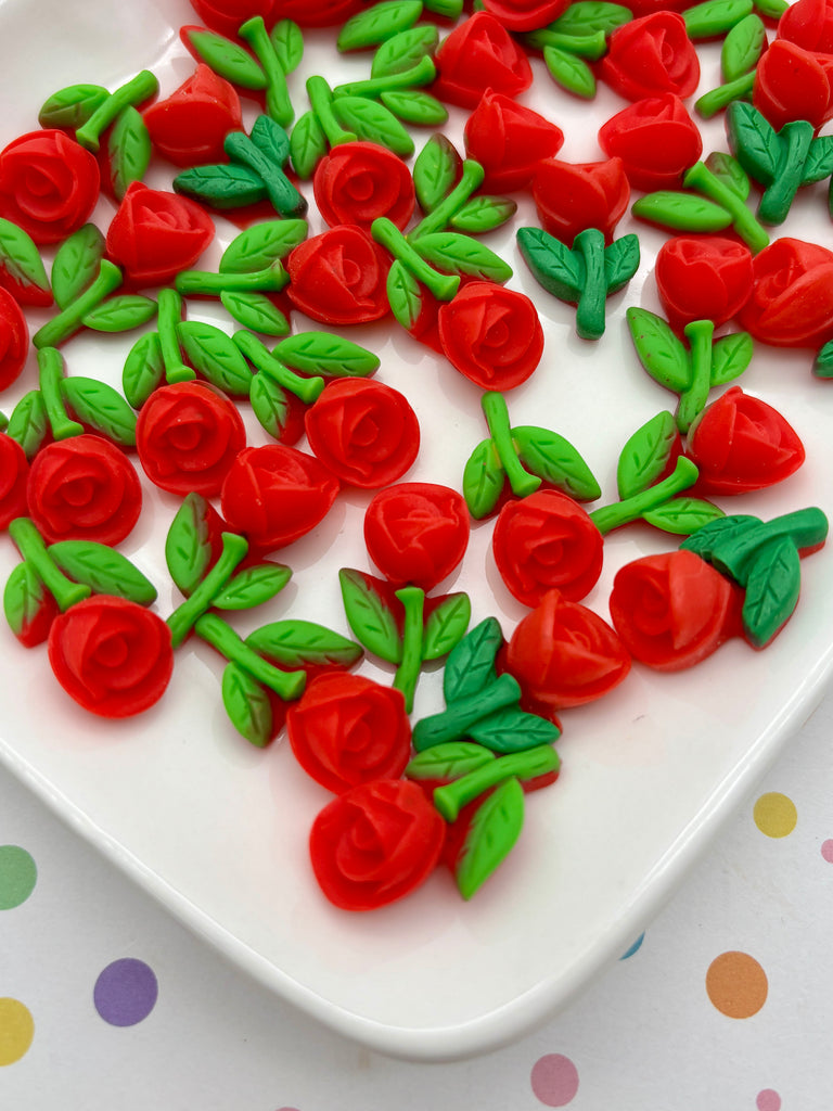 a white plate with red and green fondant roses arranged on it.