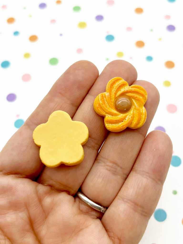 a hand holding a small yellow flower shaped brooch