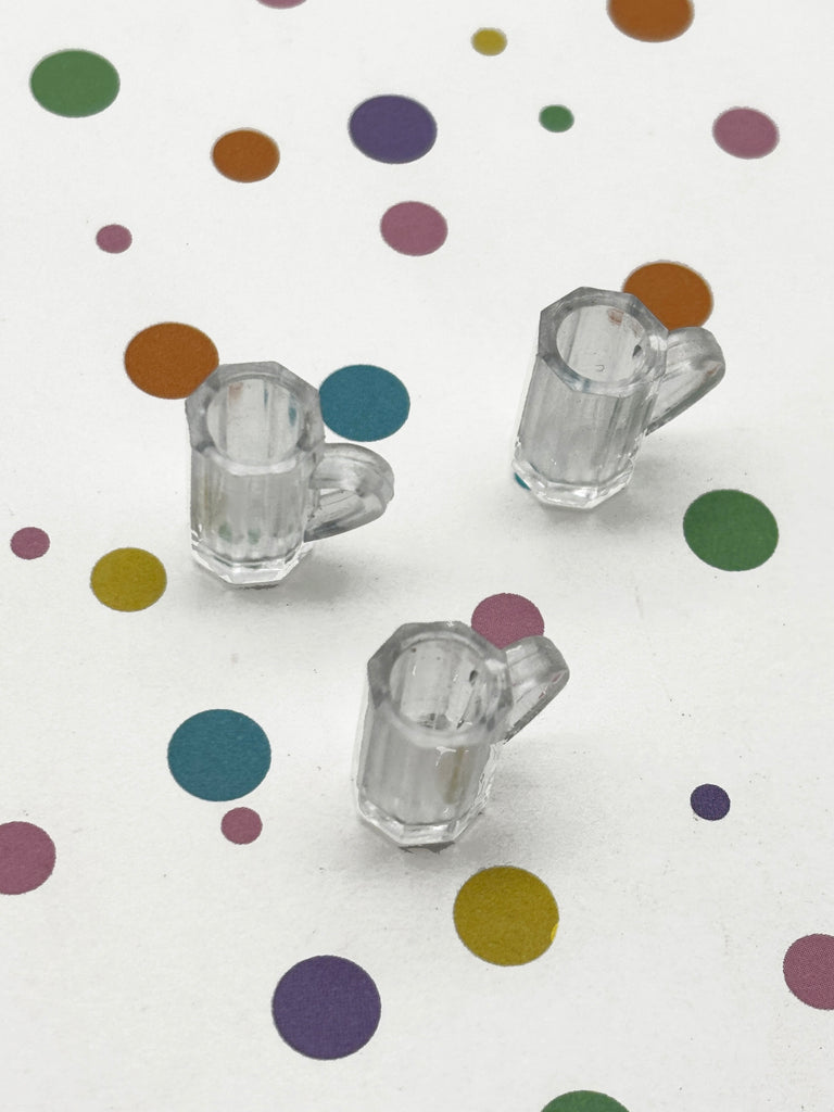 three clear glass cups arranged on a white background with colorful polka dots.