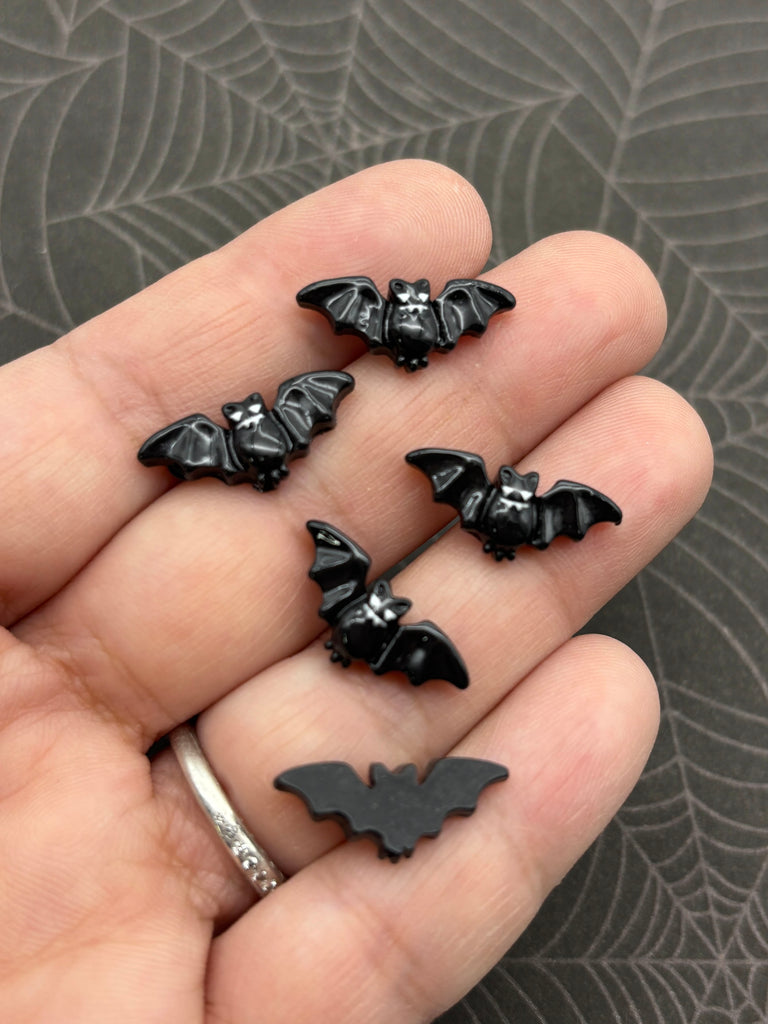 A hand holding several small black bat-shaped objects against a dark background.