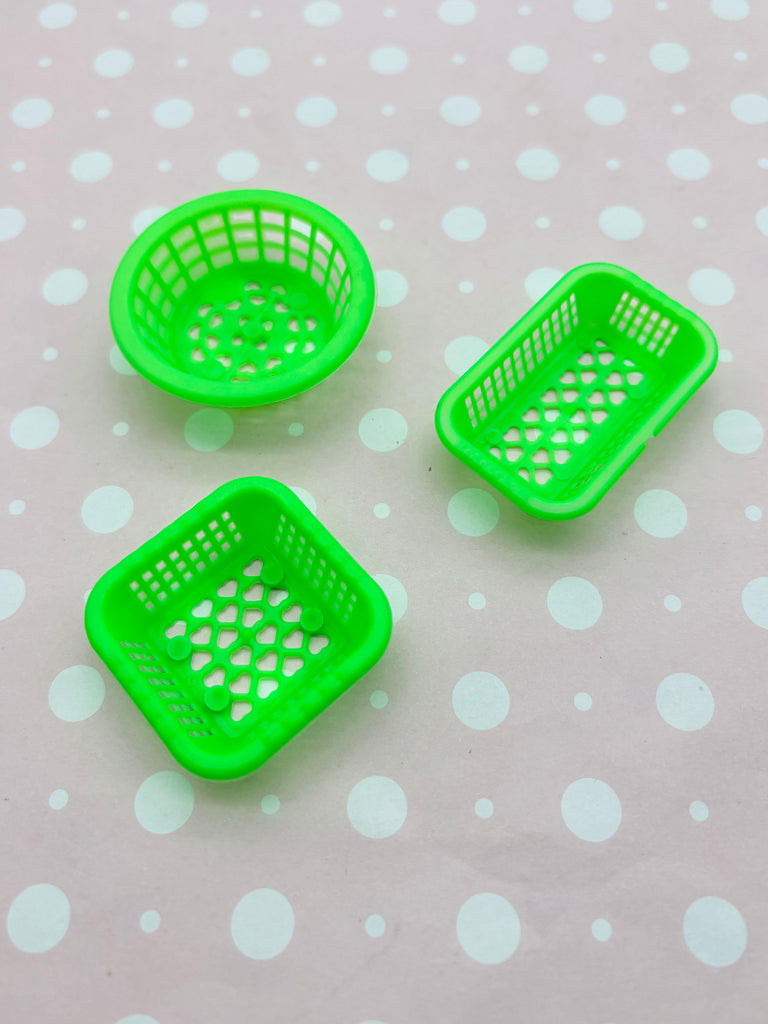 three green plastic baskets with holes on a polka dot background.