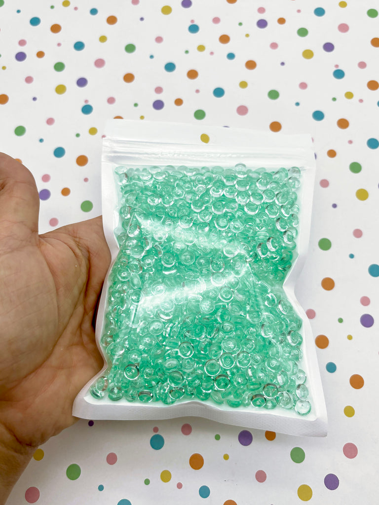 a hand holding a bag of green beads