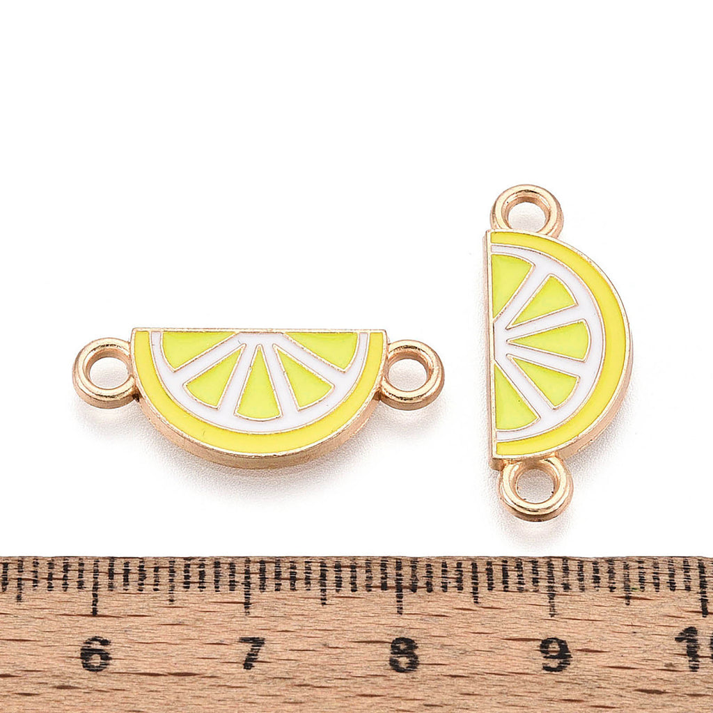 two enameled metal charms shaped like lemon slices, with a ruler placed between them to indicate their size.
