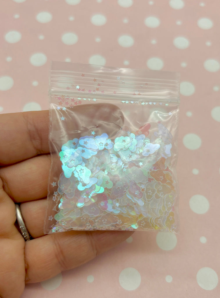 a hand holding a bag of holographics on a pink background