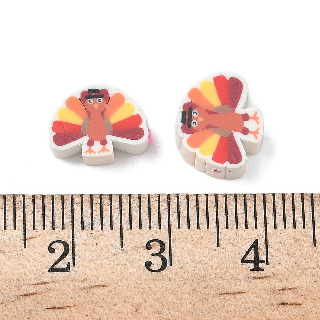 two small, colorful eraser shapes resembling turkeys, placed next to a ruler for size comparison.
