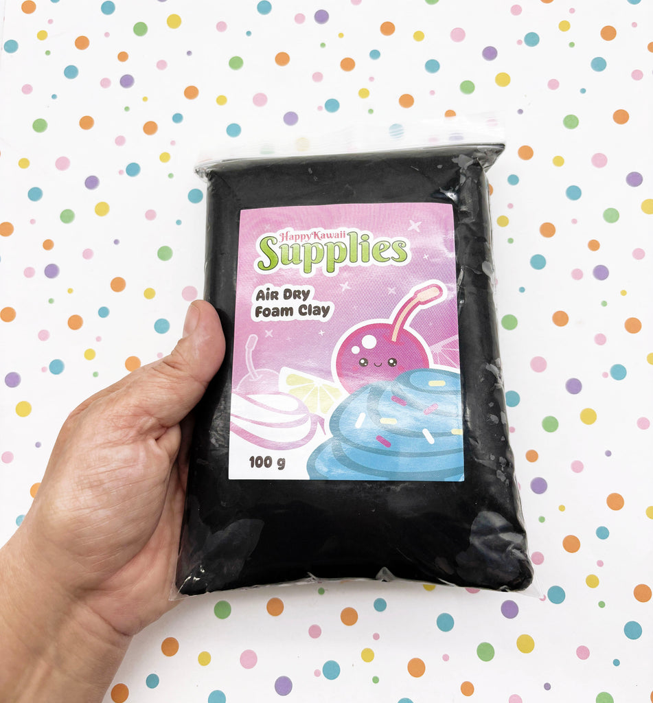 A hand is holding a bag of black foam clay with a colorful label featuring a cartoon character.