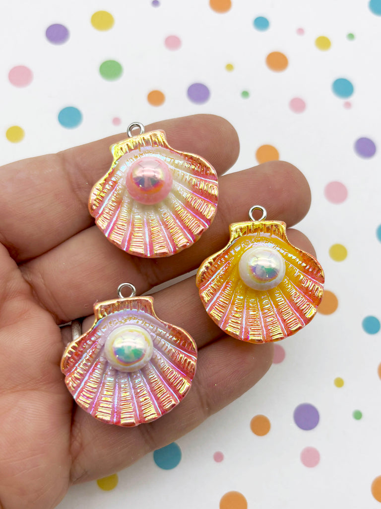 A hand holding three colorful seashell pendants against a background with polka dots.