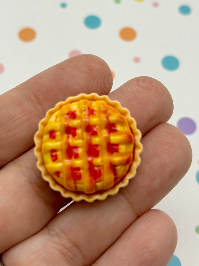 a small yellow and red pie in a persons hand