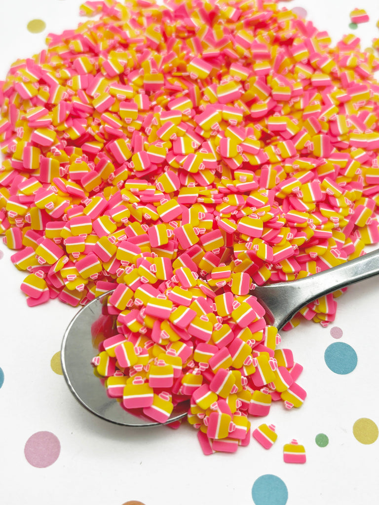 a spoon full of pink and yellow sprinkles