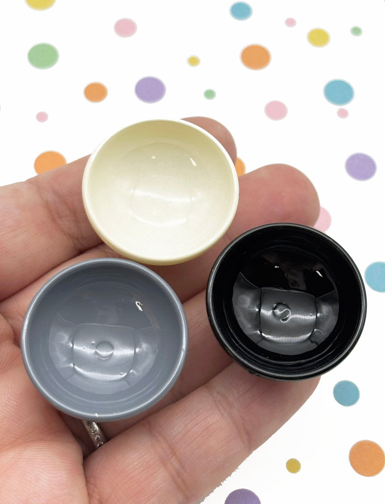 A hand holding three small bowls against a background with colorful polka dots.