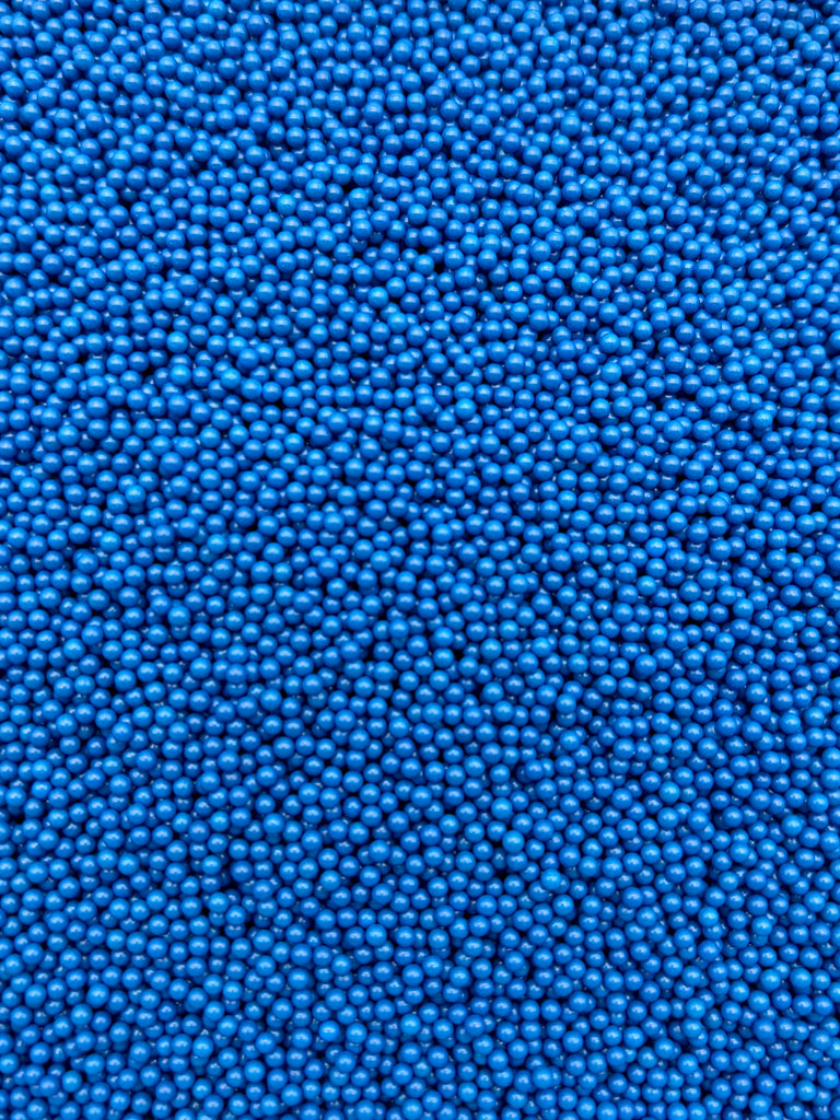 The image is a close-up of numerous small blue beads or spheres, creating a textured and visually striking pattern.