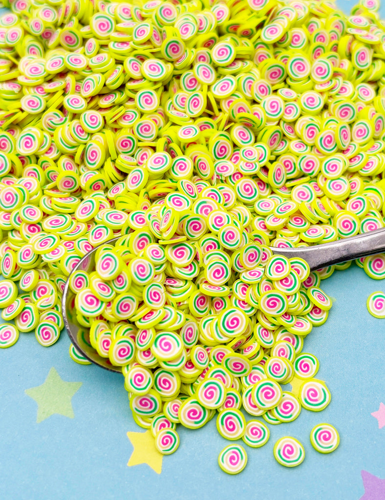 a pile of green and pink sprinkles next to a spoon
