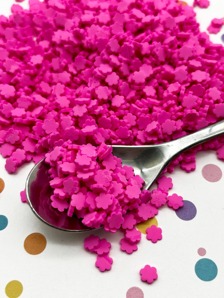 a spoon filled with pink sprinkles on top of a table