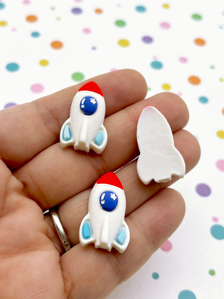 a person holding two small toy rockets in their hand