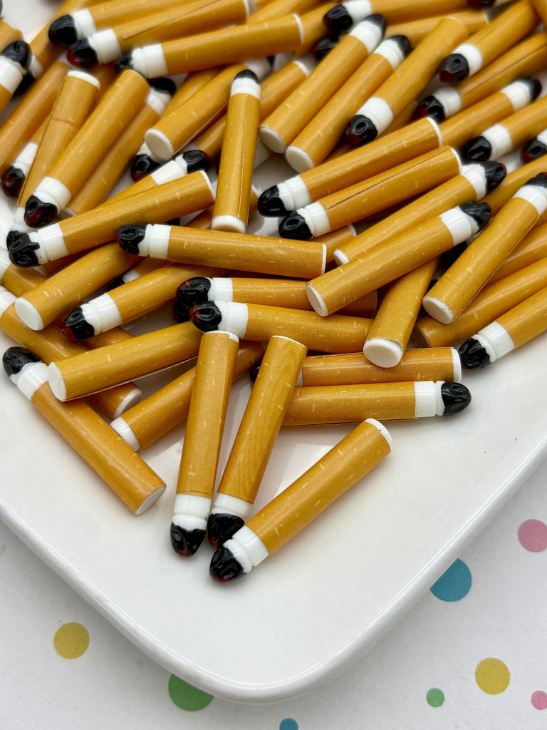 a white plate filled with numerous cigarette-shaped objects, resembling the appearance of actual cigarettes.