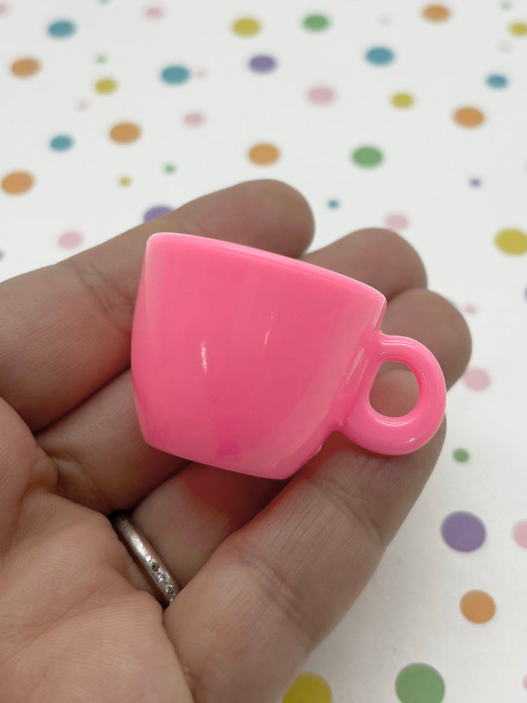 a hand holding a small pink cup in it's palm