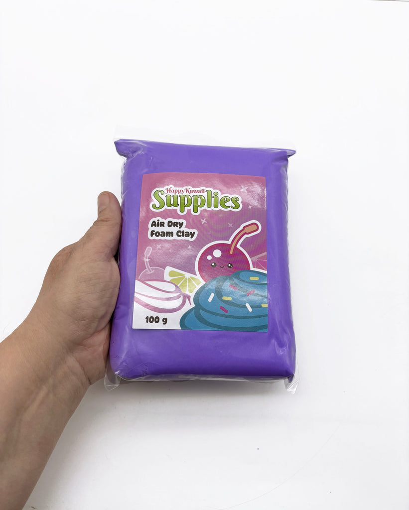 A hand is holding a package of air dry foam clay, which is a purple-colored material.