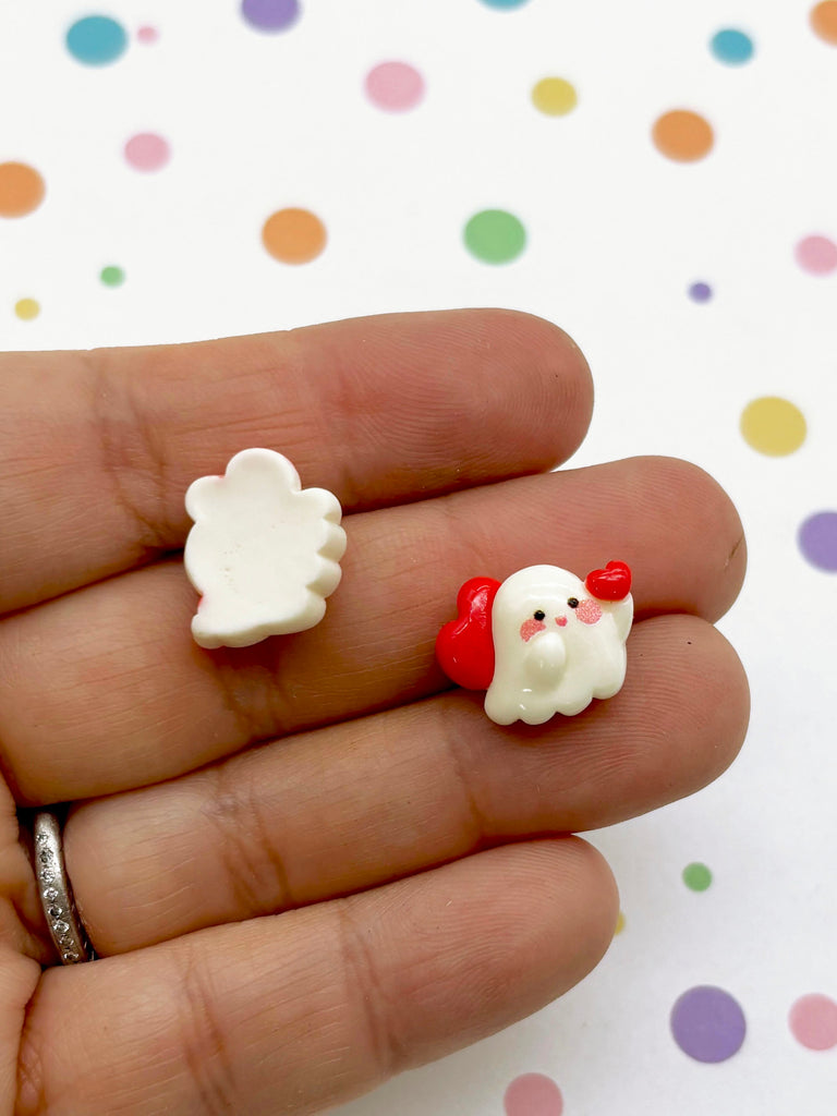 a hand holding two small white and red items