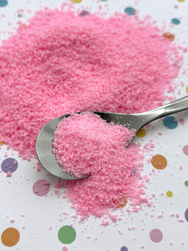 a spoon full of pink sugar on top of a table