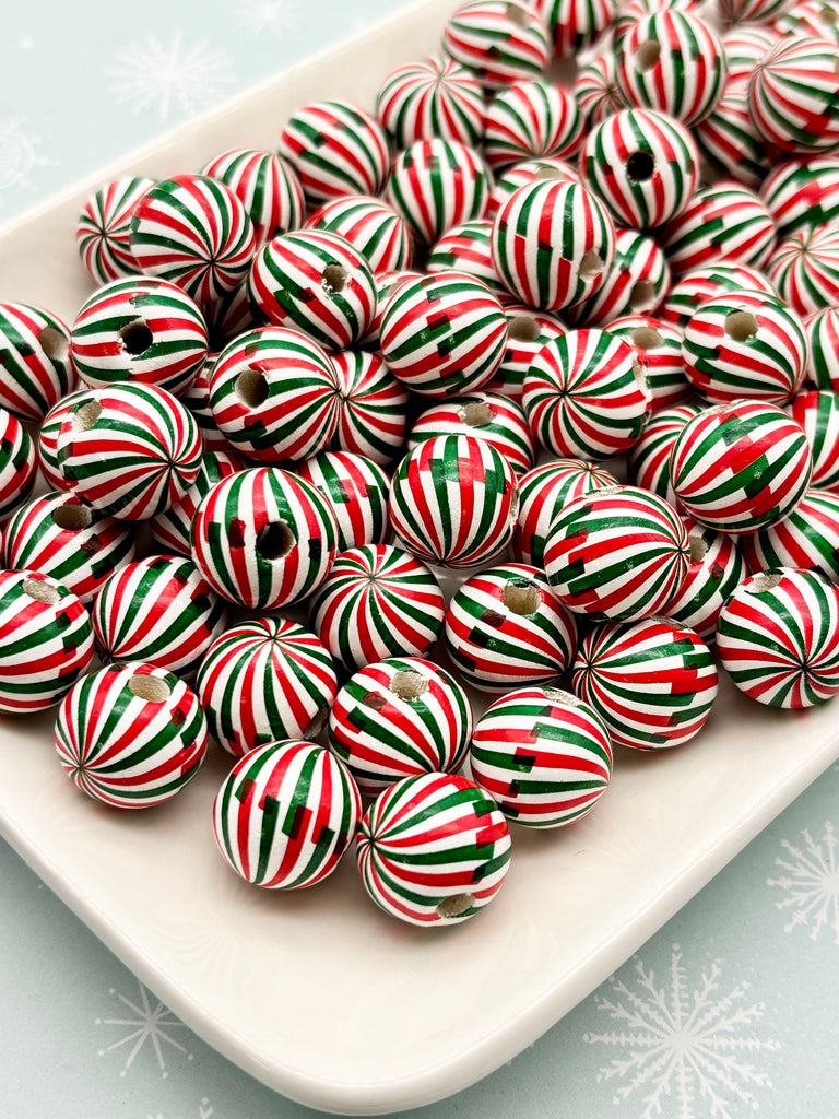 a white plate filled with numerous red, green, and white striped beads, creating a festive and colorful display.
