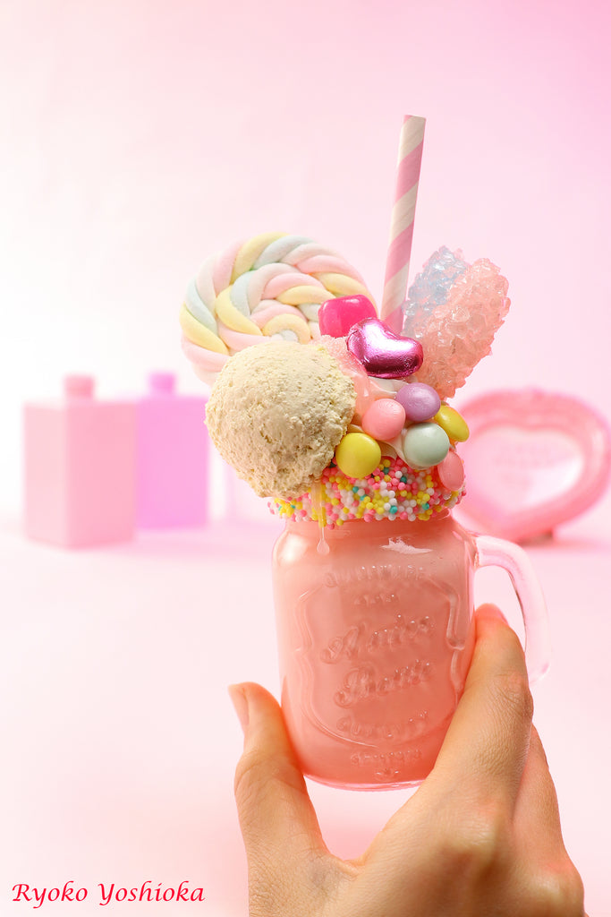 a person holding a cup with candy and marshmallows in it