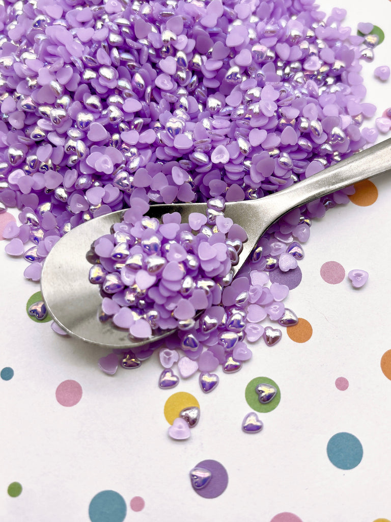 a spoon filled with purple sprinkles on top of a table