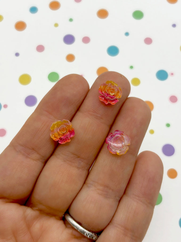 a hand holding a pair of pink and yellow flowers