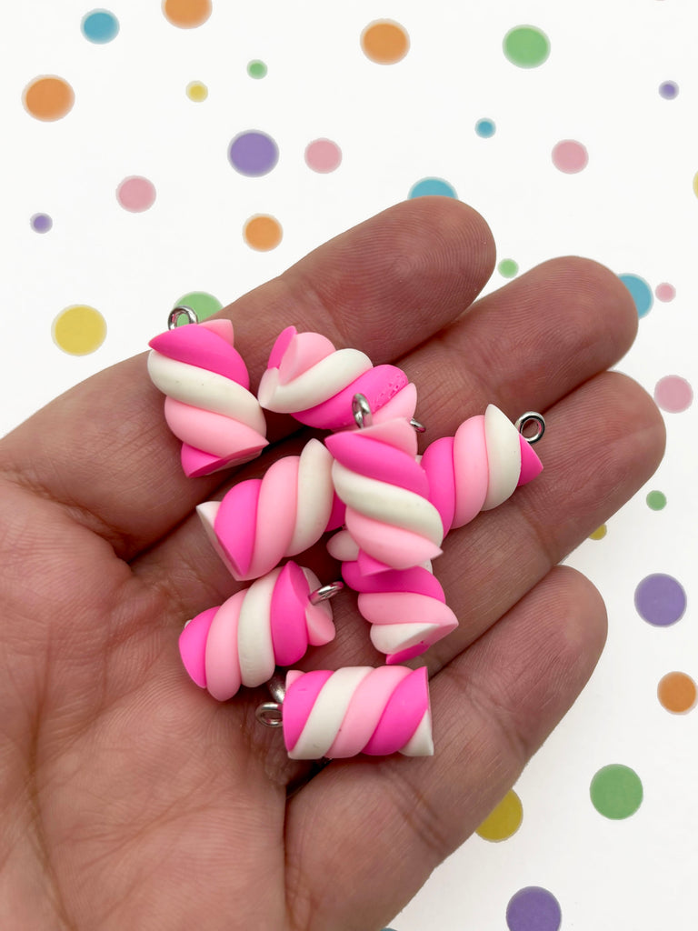 A hand holding several colorful, twisted marshmallow-like objects against a background with polka dots.