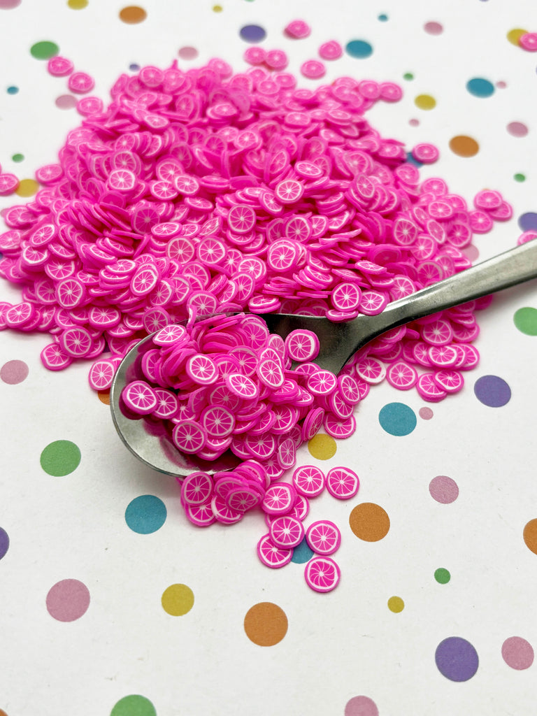 a spoon full of pink buttons sitting on top of a table