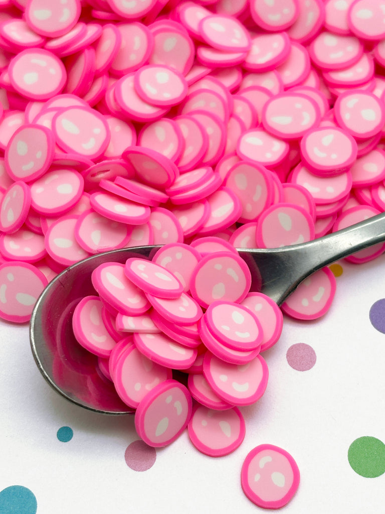 a spoon filled with pink candy hearts on top of a table