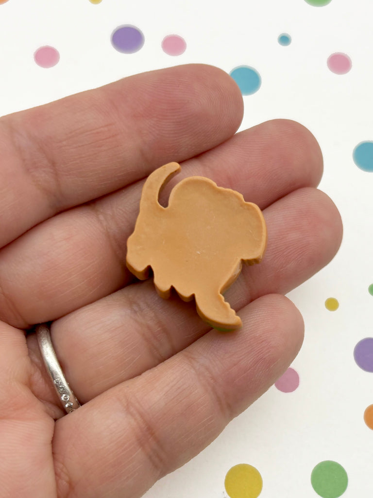 A hand holding a small, light brown object resembling a cat or a similar animal shape.