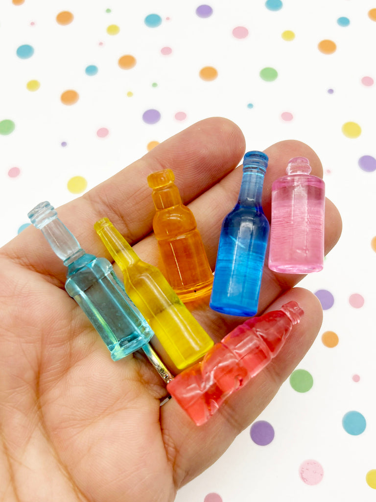 a hand holding a small group of small plastic bottles