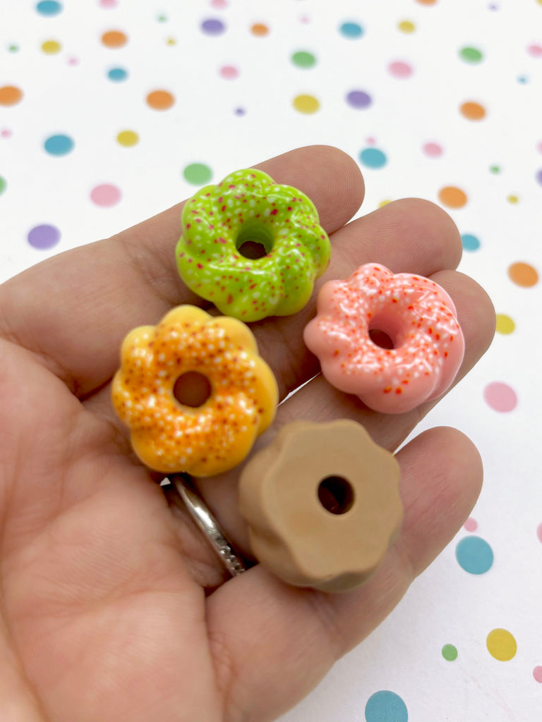a person holding three miniature donuts in their hand
