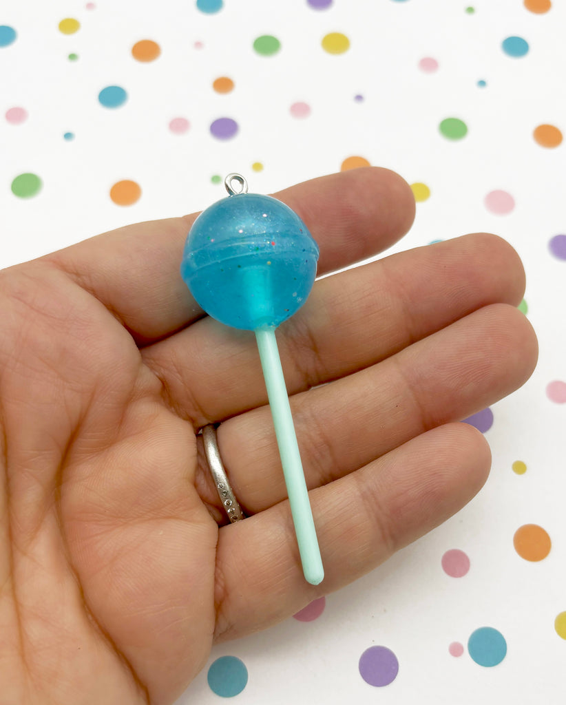 a hand holding a blue candy lollipop in it's palm