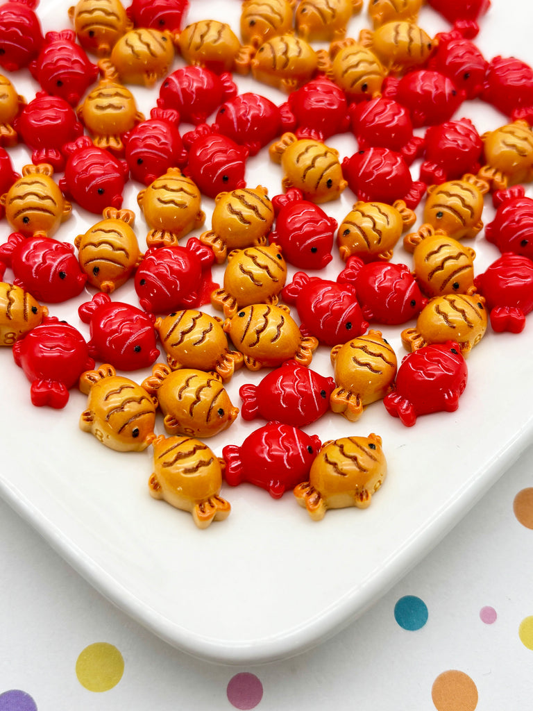 a white plate with a variety of colorful fish-shaped candies arranged on it.