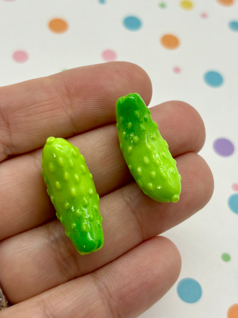 a hand holding a small green toy pickle in it's palm