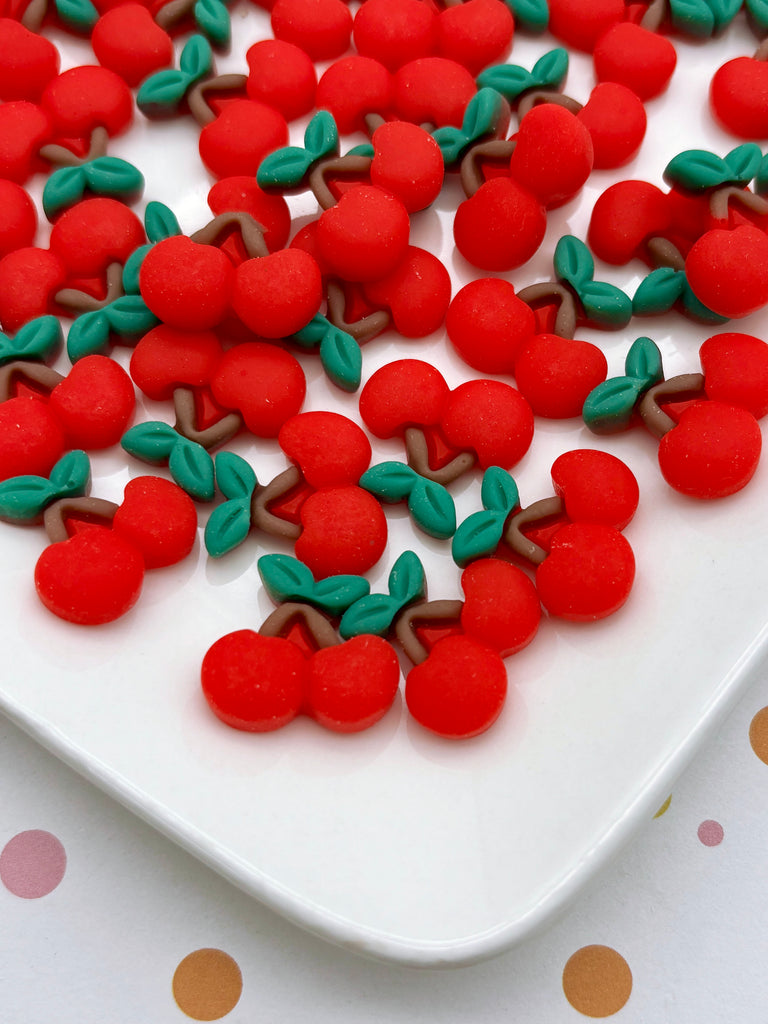 a white plate with a variety of red and green cherries arranged on it.