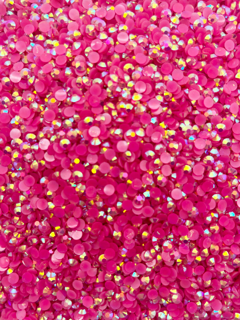 The image is a close-up of a pile of pink glittery beads or sequins, creating a vibrant and sparkling visual effect.
